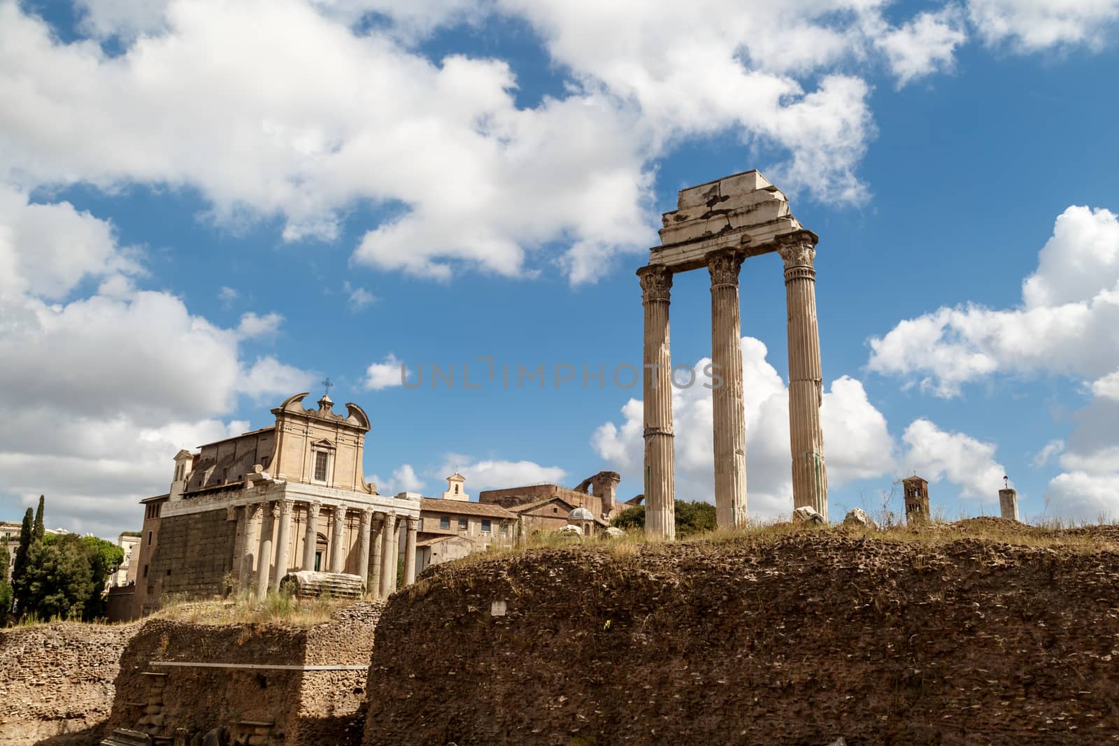 View of archeological area of ancient Roman Forum in Rome, on cloudy blue sky background.