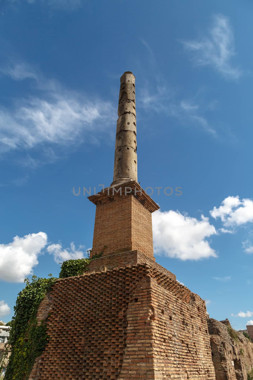 Detailed view of column in ancient Roman Forum in Rome, on cloudy blue sky background.