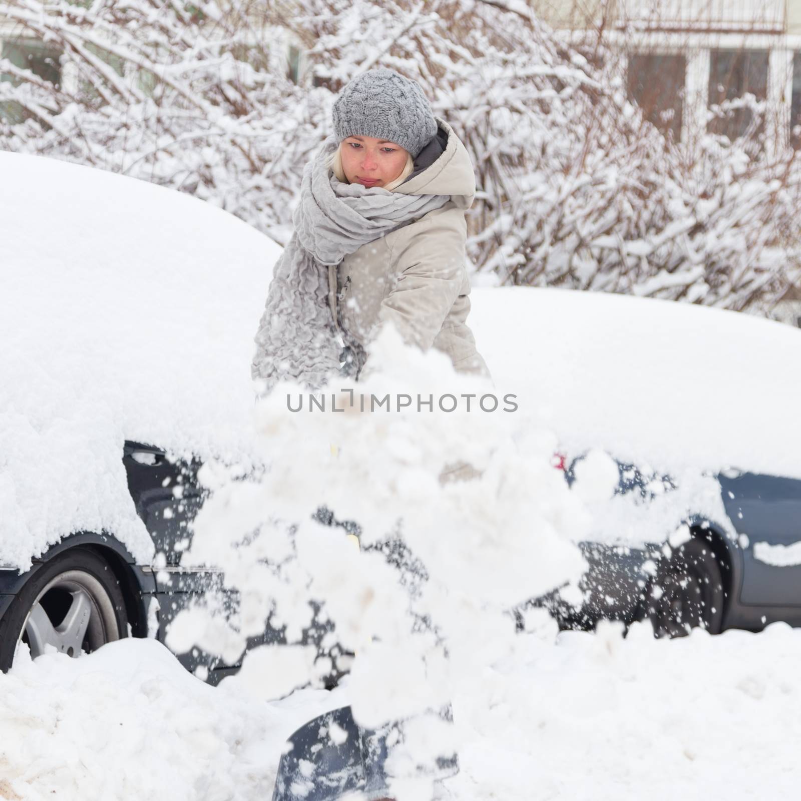Independent woman shoveling snow in winter. by kasto