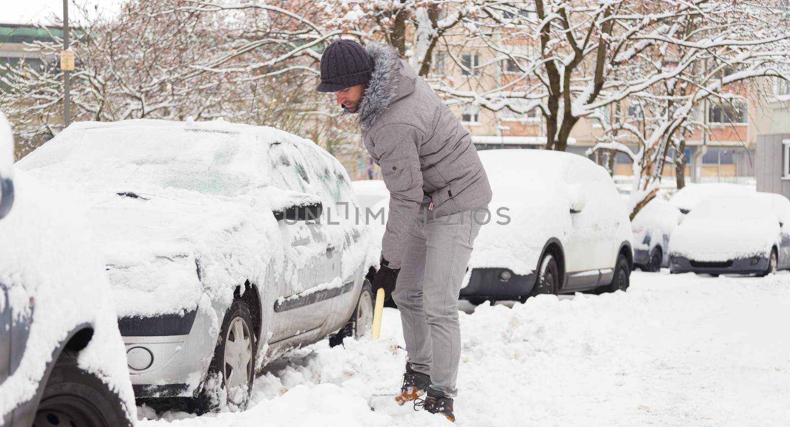 Man shoveling her parking lot after a winter snowstorm.