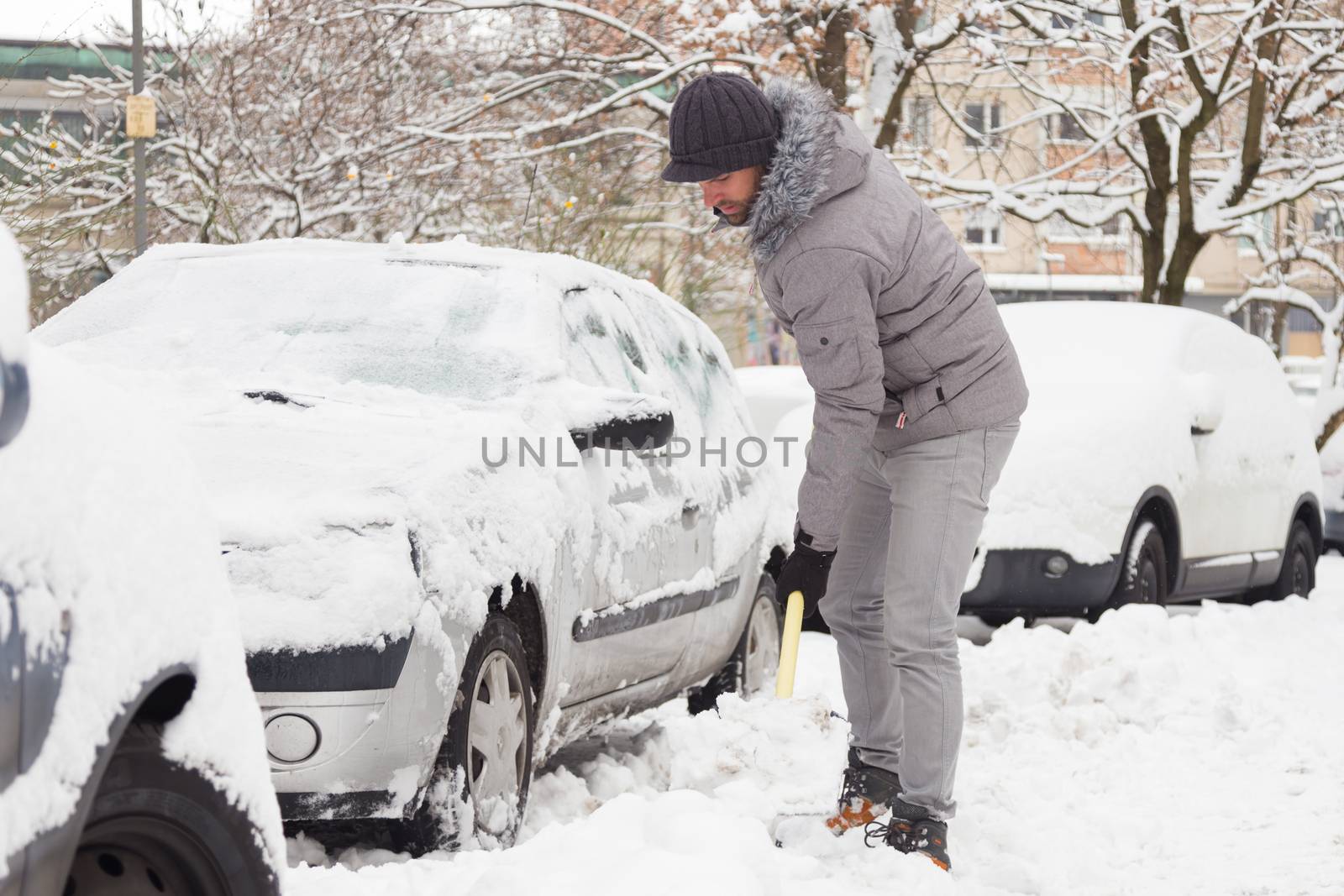 Man shoveling her parking lot after a winter snowstorm.