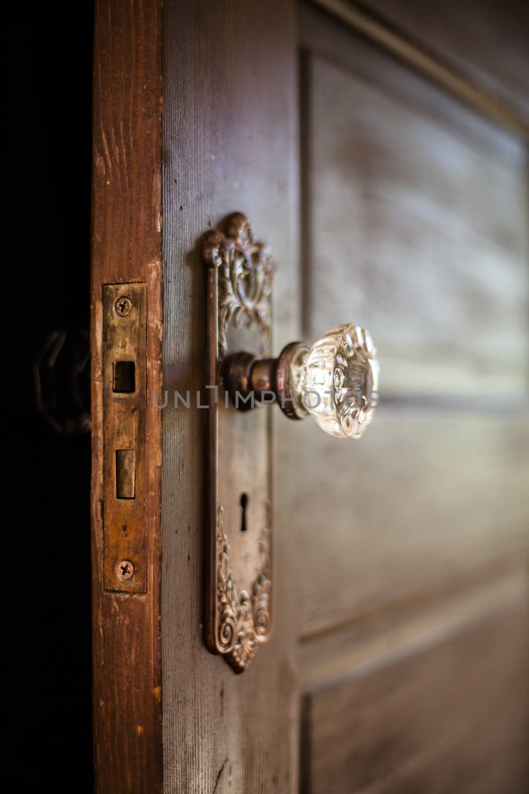 An old door, open with an ornate door knob.