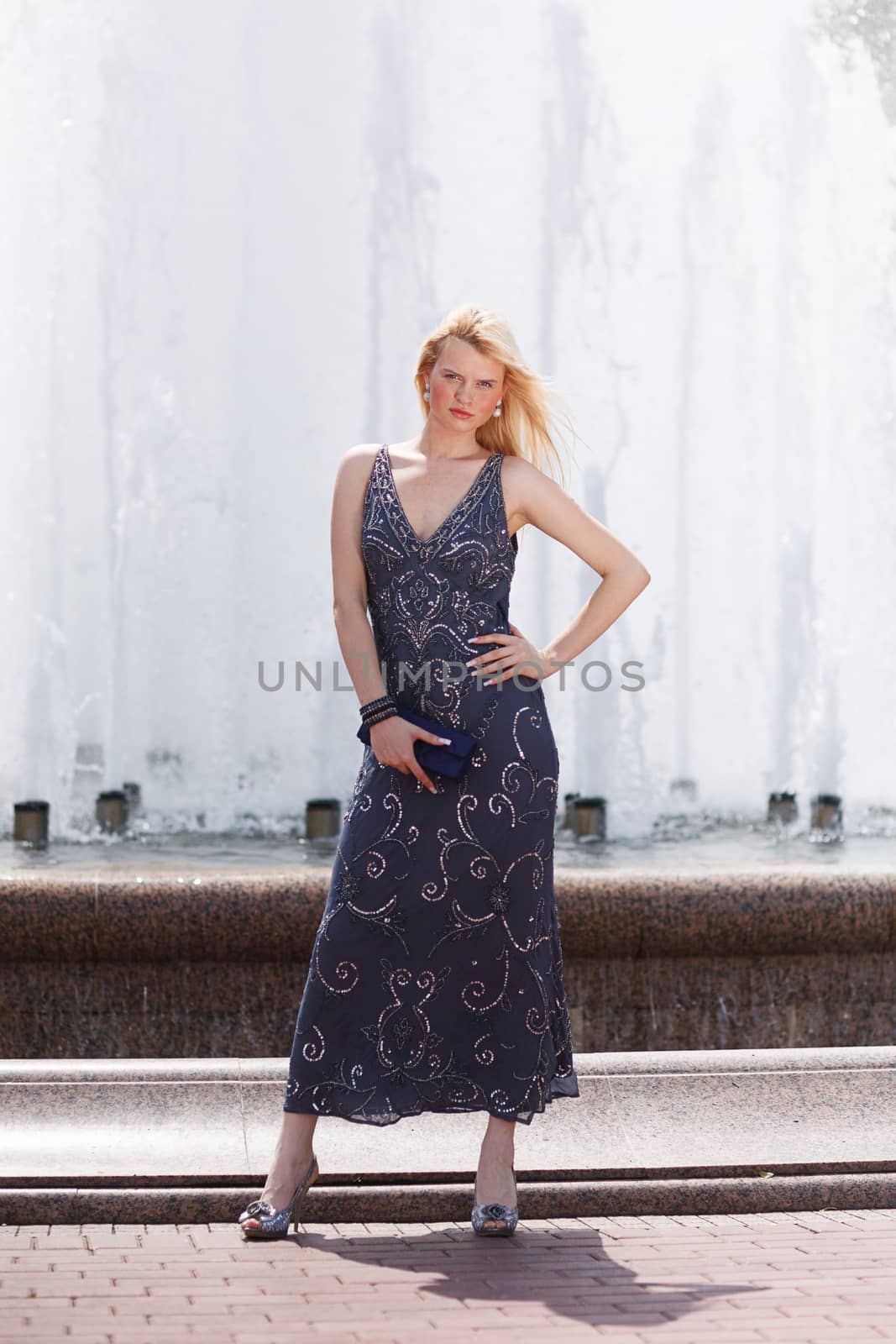 Blond woman in glitter dress next to fountain