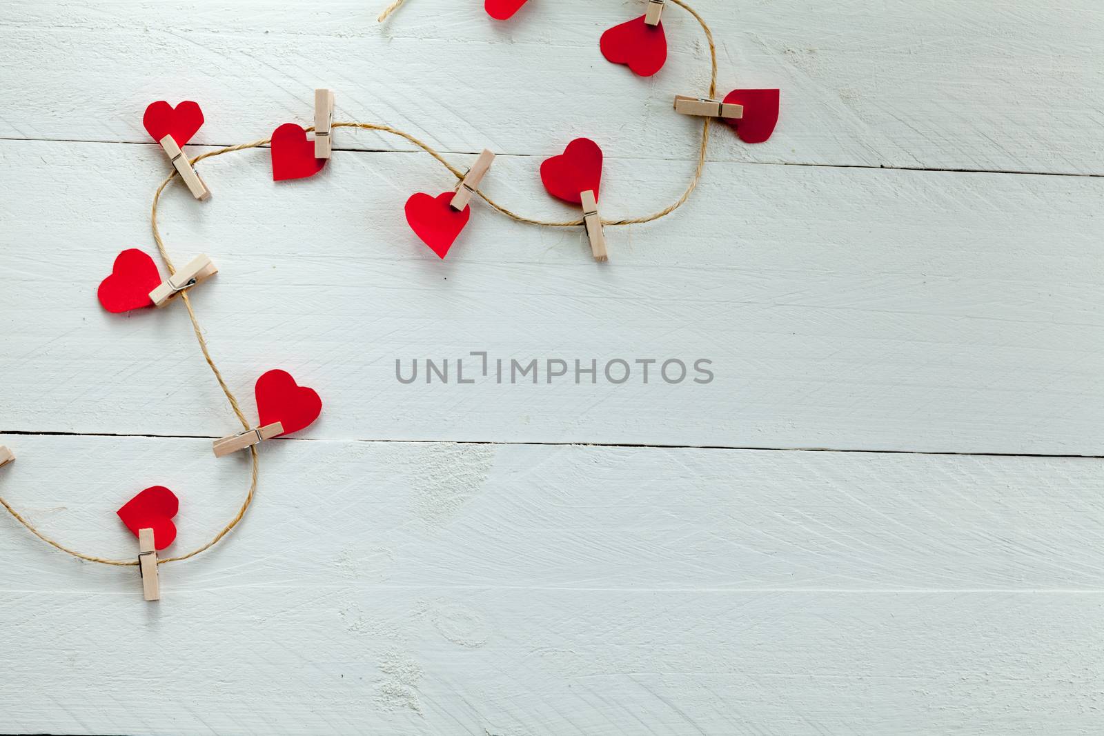 Red hearts subjects with tweezers on white wooden background