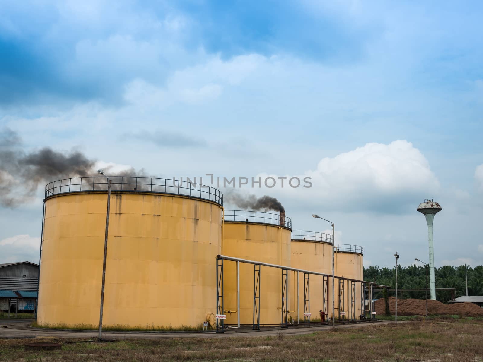 Metal oil tanks in Palm oil refinery plant and puffs of smoke, Thailand.