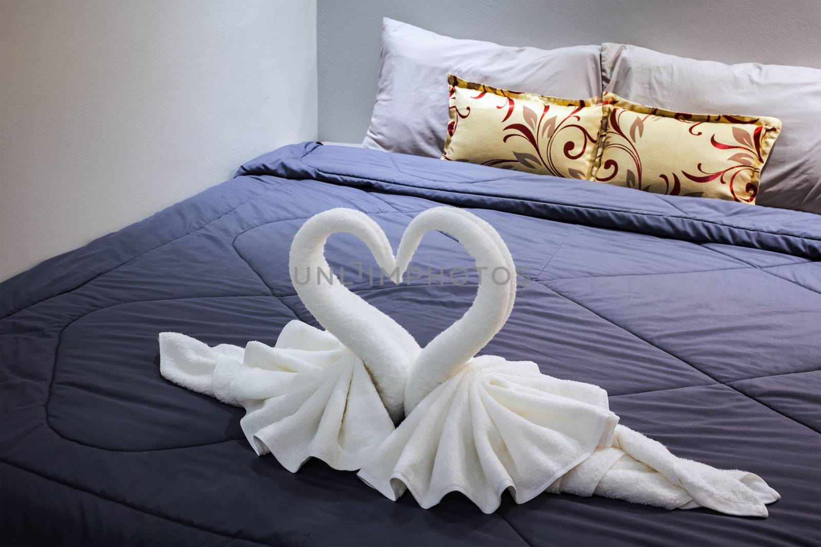 towel folded in swan shape on bed sheet by FrameAngel