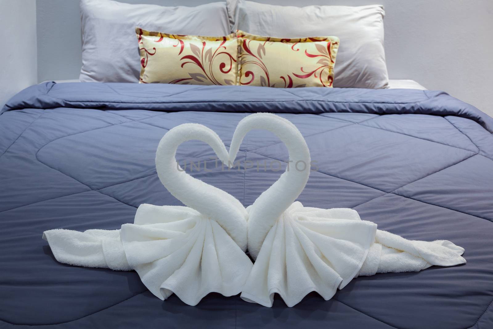 towel folded in swan shape on bed sheet by FrameAngel