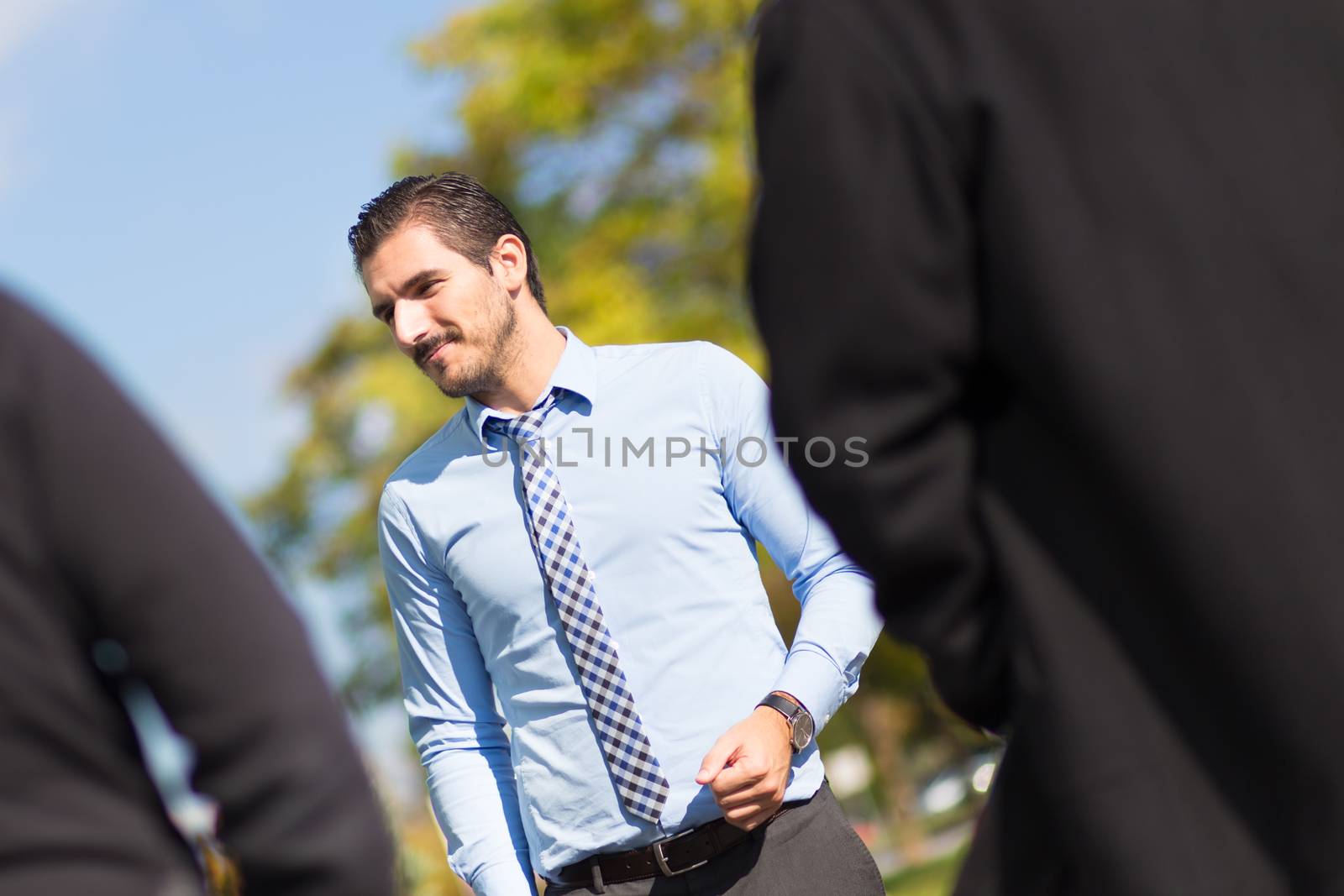 Attractive young businessman with a friendly smile having informal out of office meeting on a suny day.