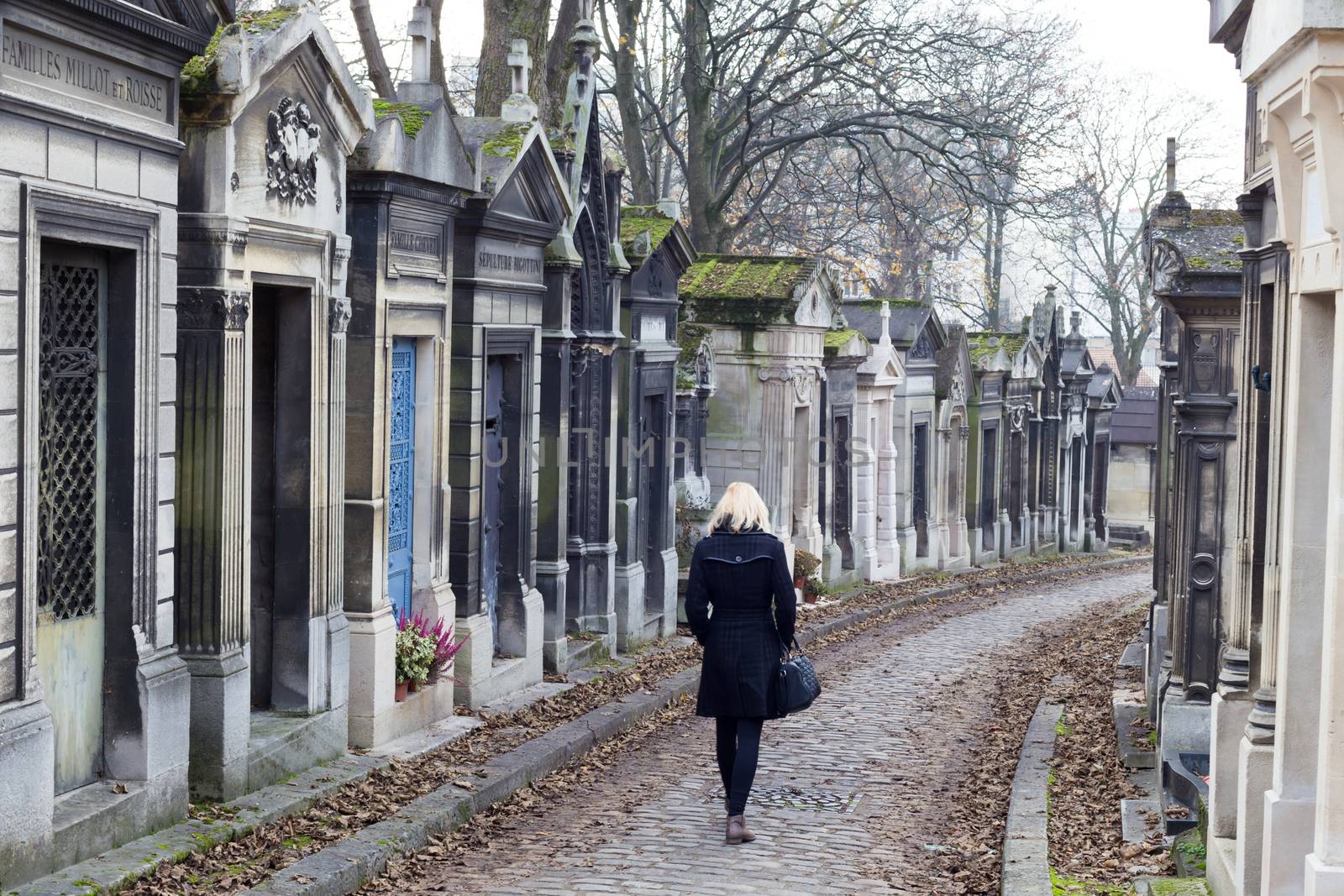 Solitary woman remembering dead relatives in on Pere Lachaise cemetery in Paris, France.