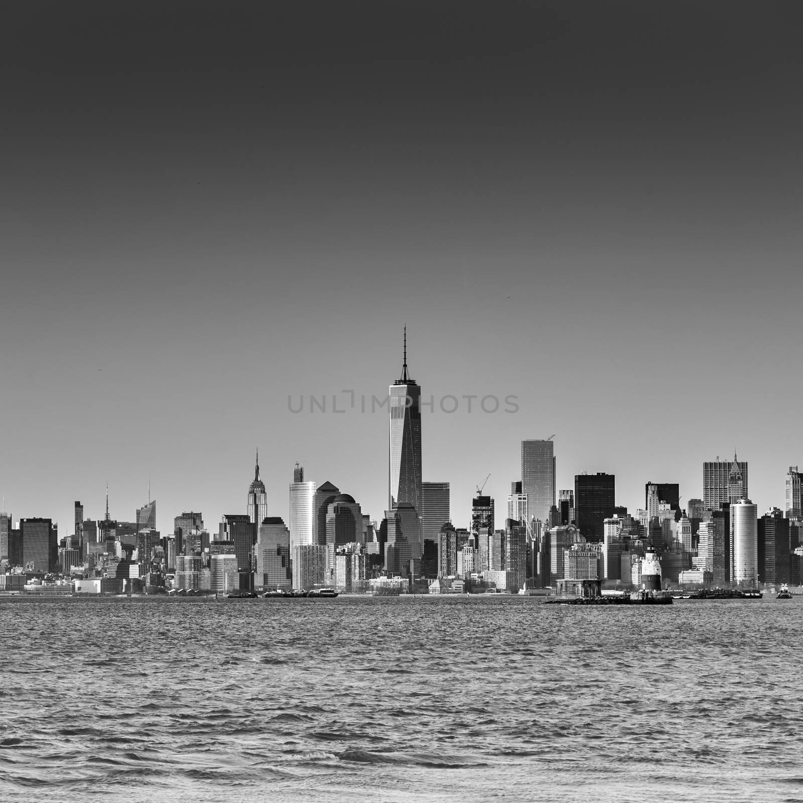 New York City Manhattan downtown skyline at dusk with skyscrapers illuminated over Hudson River panorama. Square composition, copy space. Black and white image.