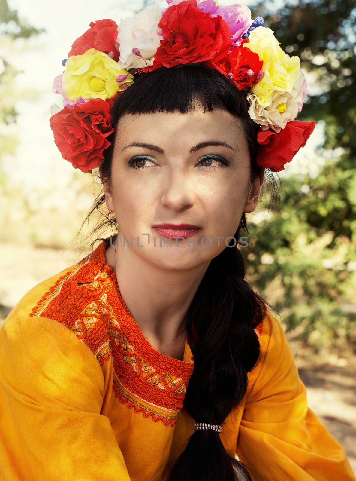 charming woman in wreath of roses on her head on the background of nature