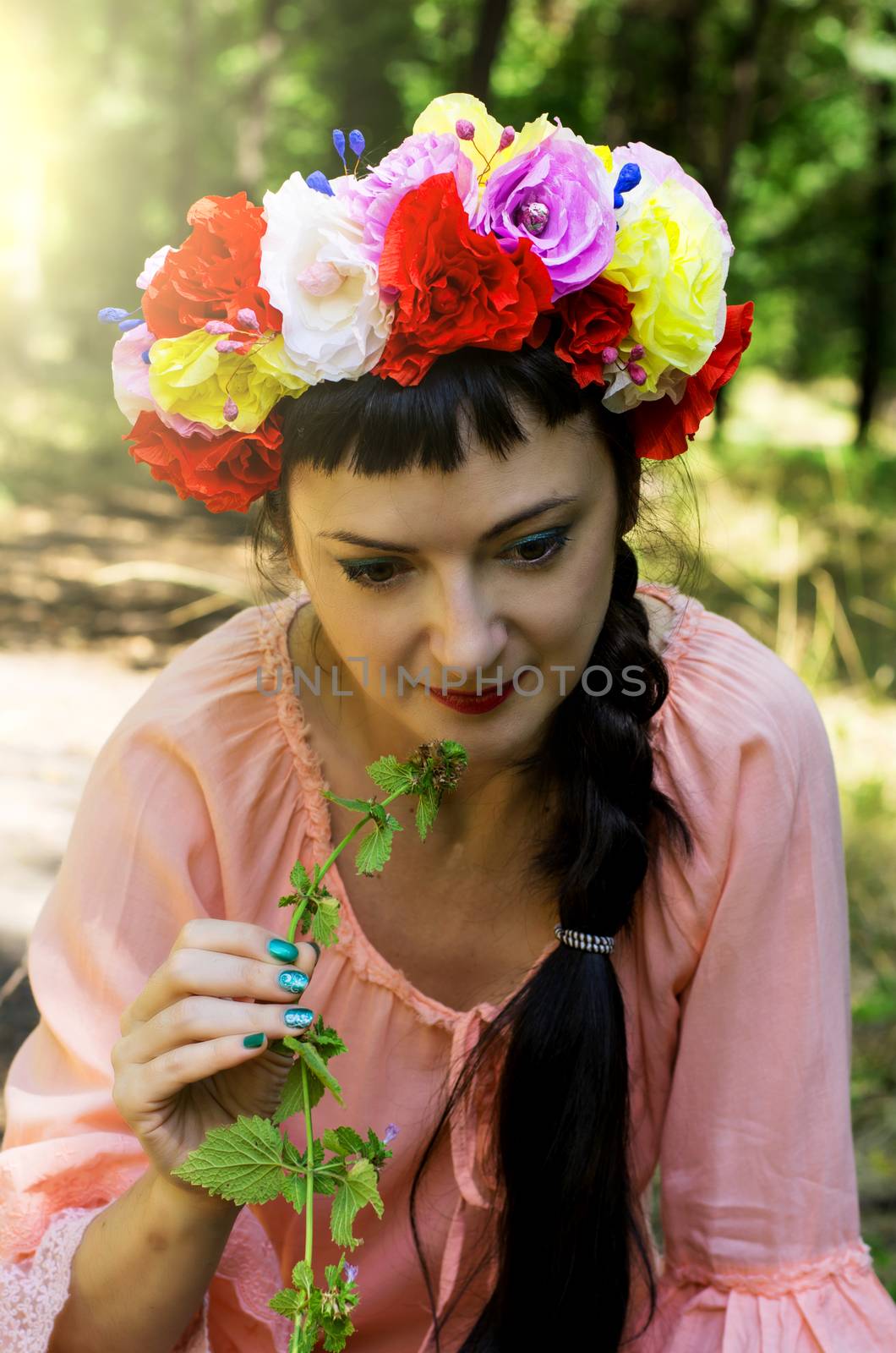 charming woman in wreath of roses on her head on the background of nature
