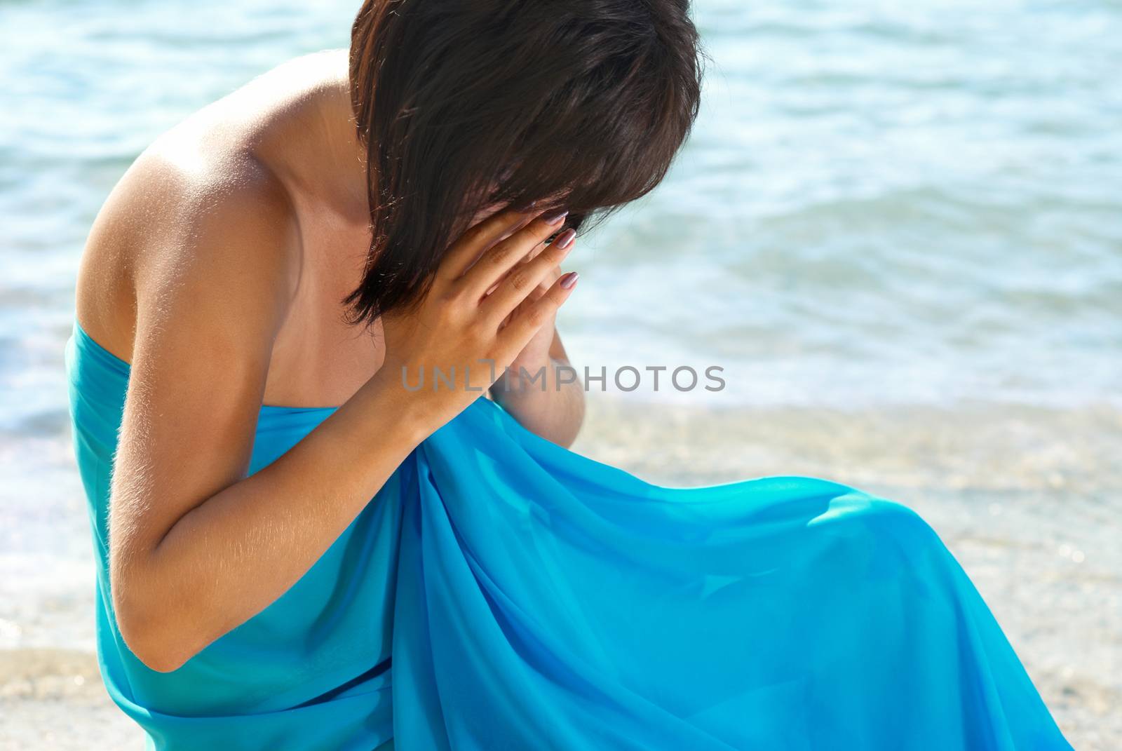 Young woman crying on the beach with water background