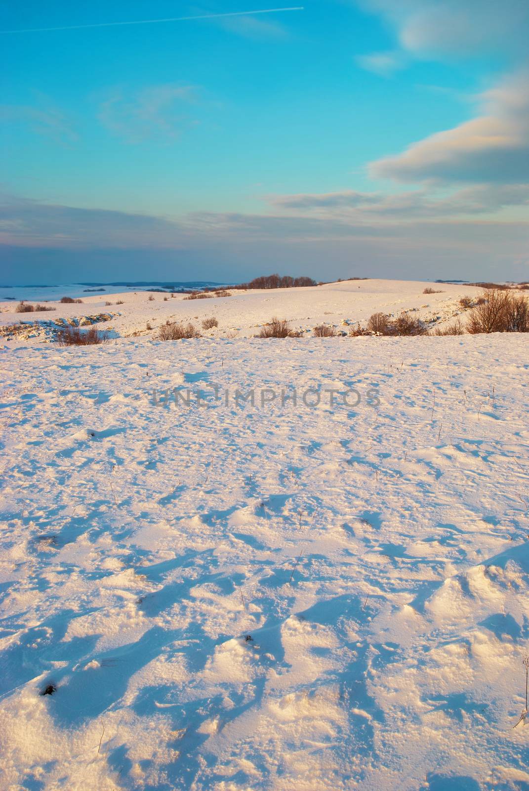 Winter hills covered by snow against sunset