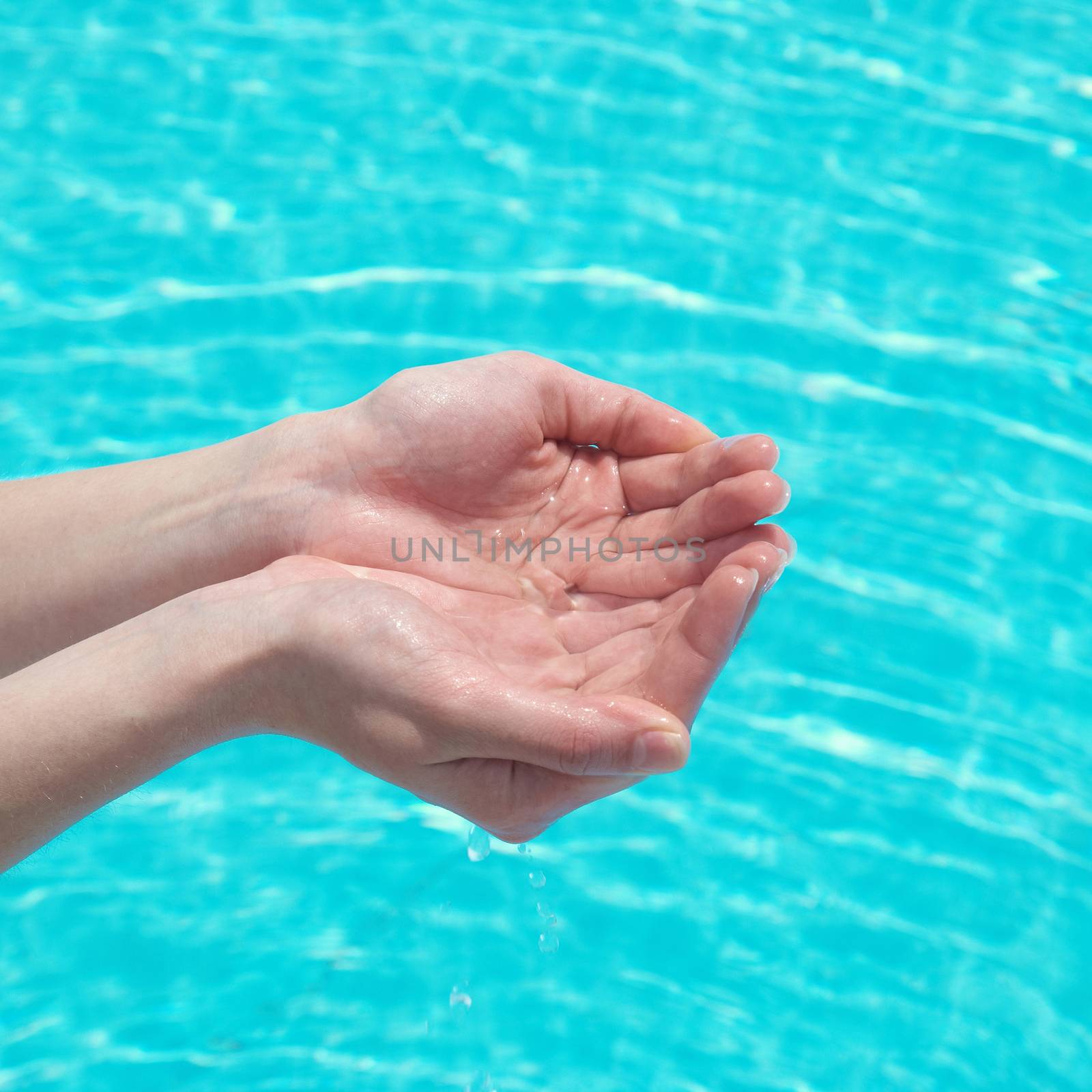 Human hands with clear water on the blue background