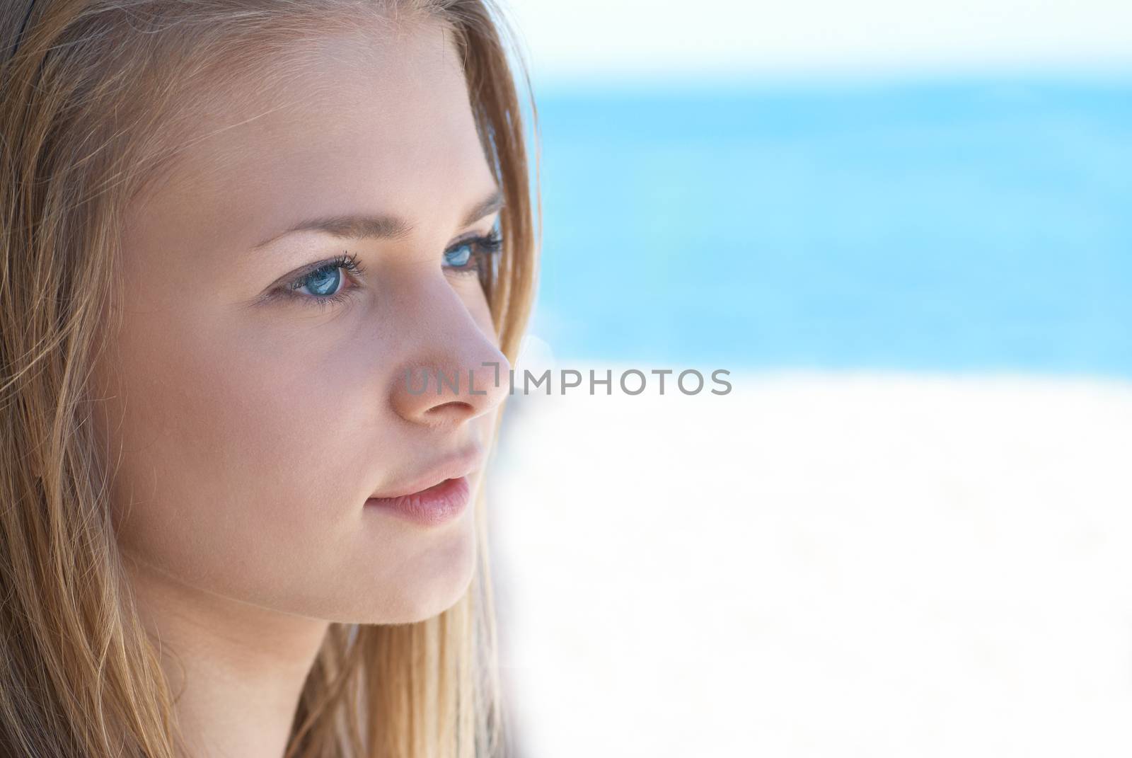 Beautiful blond hair girl with blue eyes outdoors against the sea