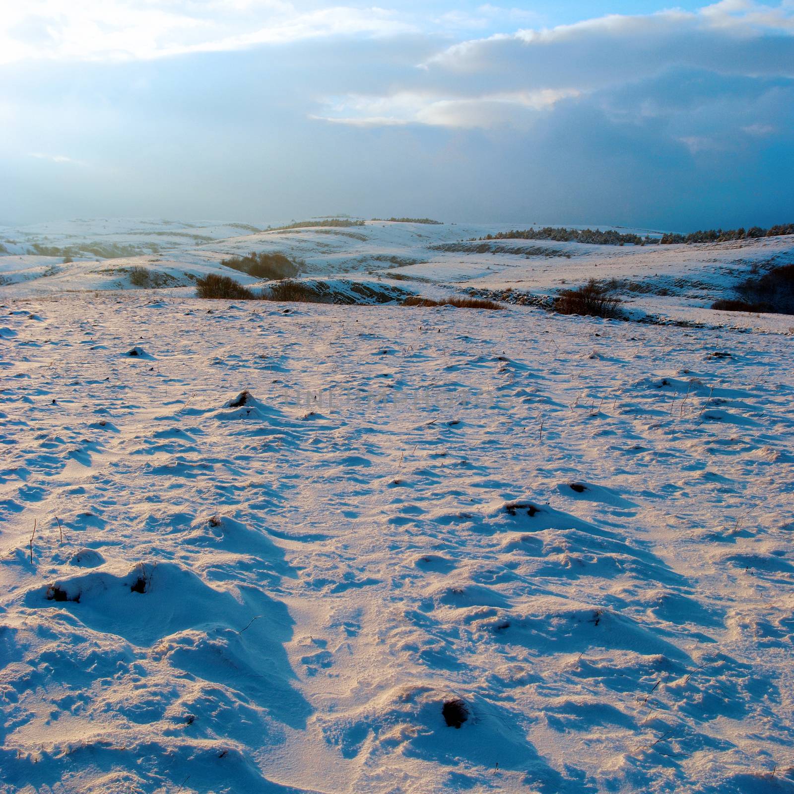 Winter hills covered by snow against sunset