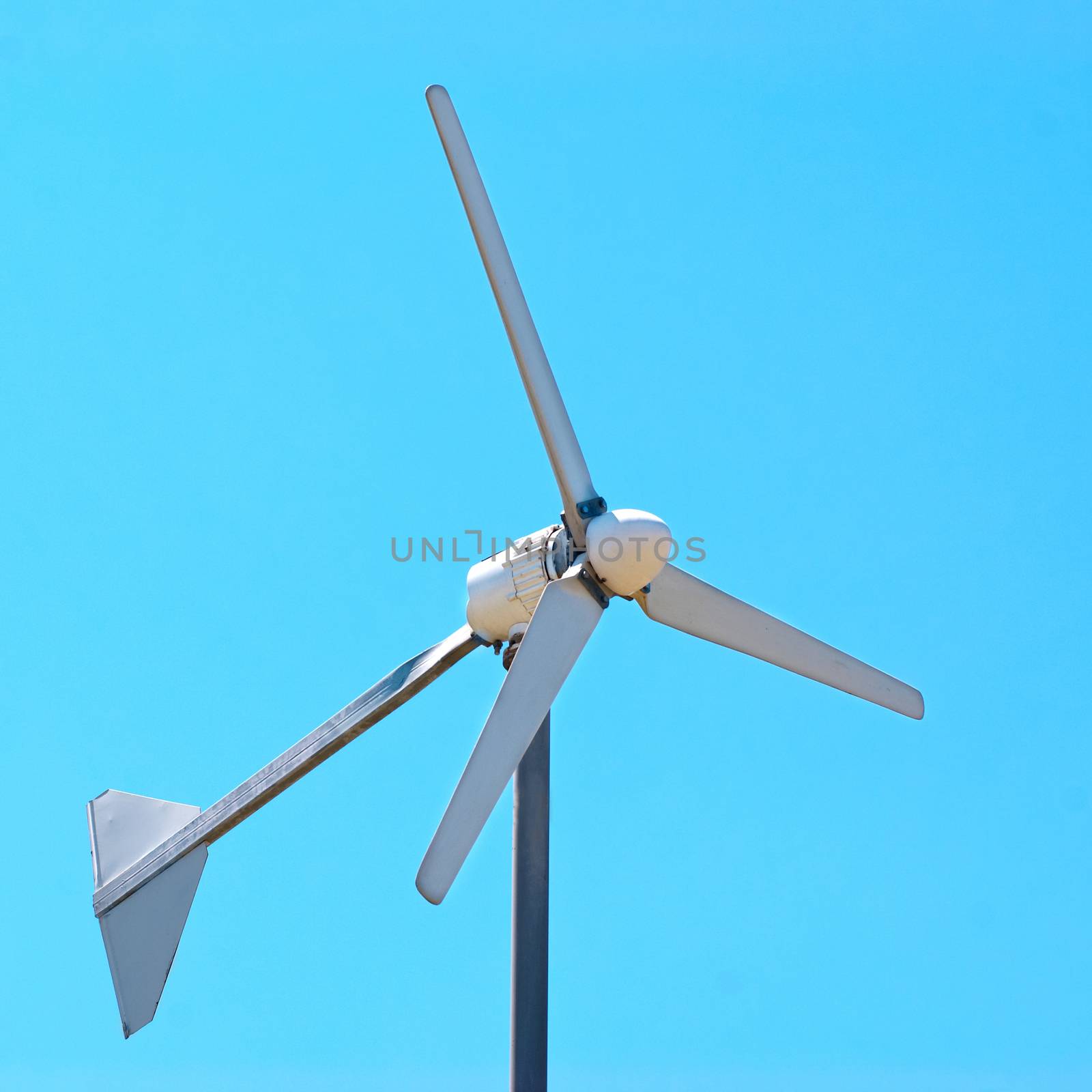 Wind electric turbine generator at blue sky background