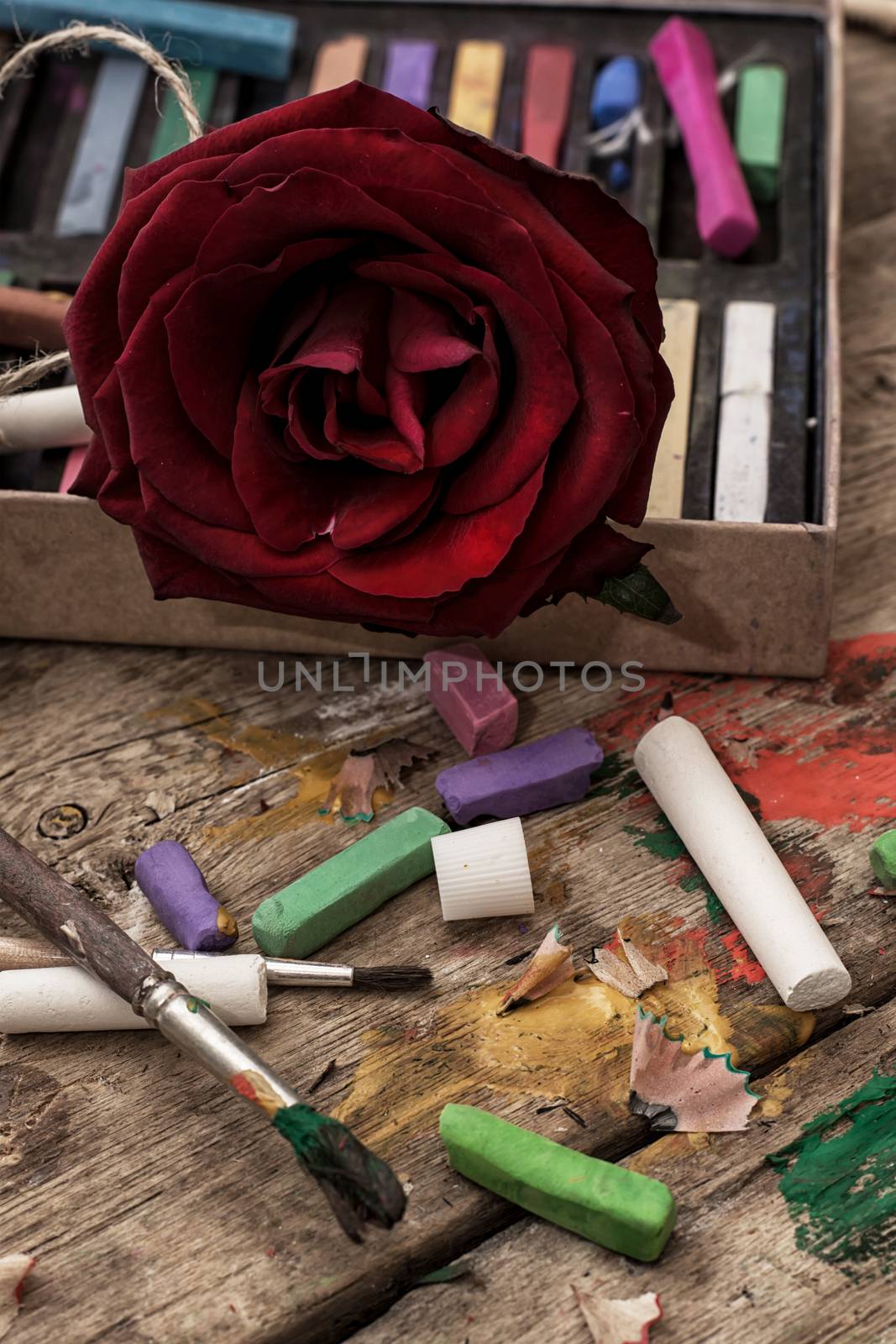Crayons and paints for painting on wooden background
