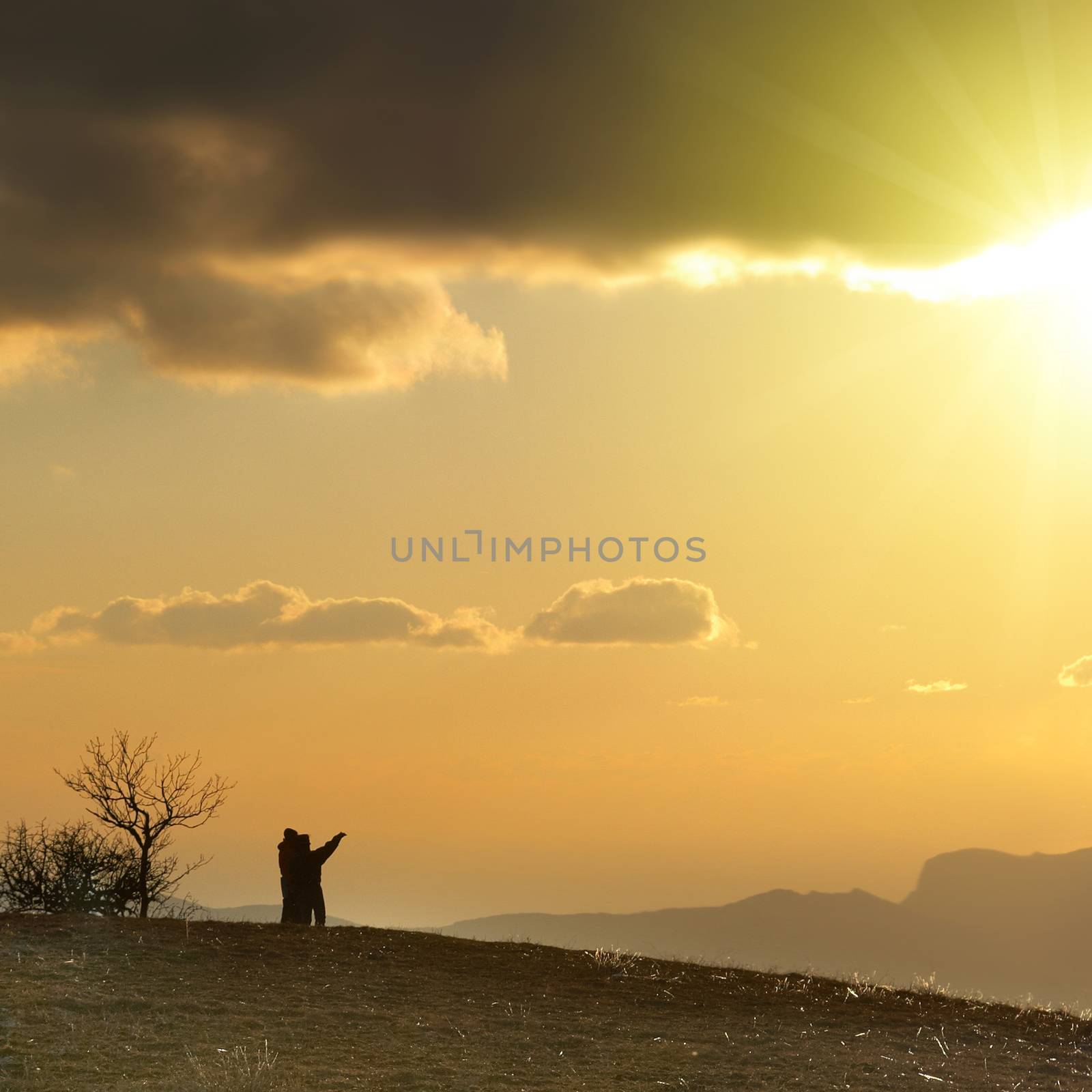 Couple on the hill against sunset. Landscape with clouds and sky.