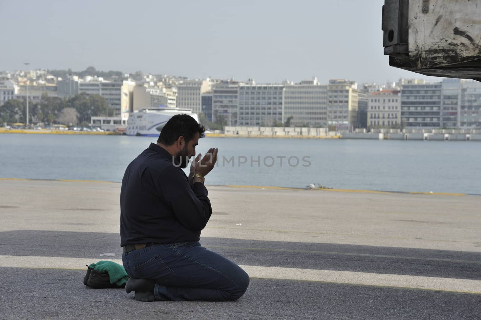 GREECE, Piraeus: A migrant prays after arriving from the islands at the port of Piraeus, on March 1, 2016, in Greece. Border restrictions further north in the Balkans have left thousands of refugees and migrants stranded in Greece.