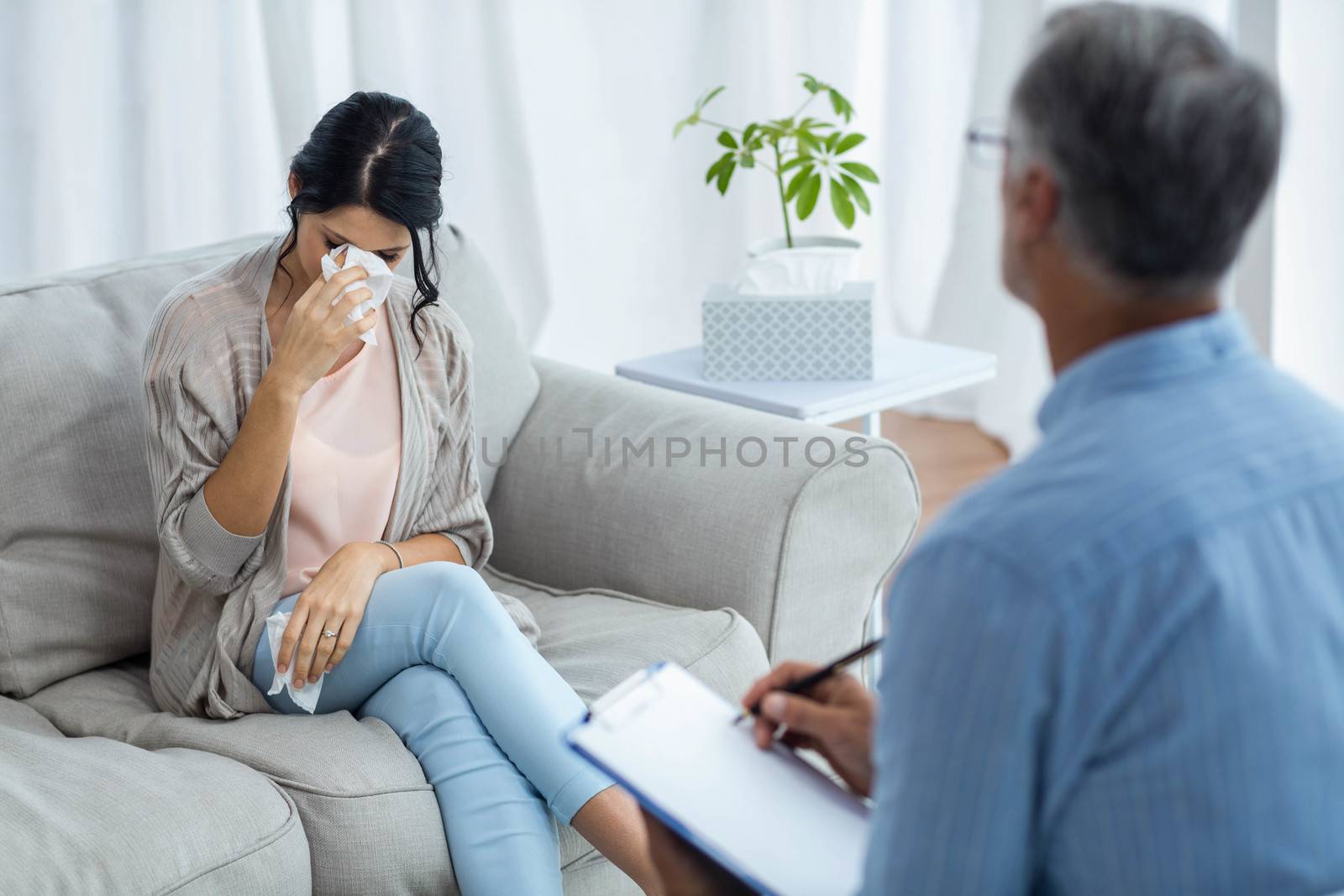 Doctor writing on clipboard while consulting pregnant woman at home