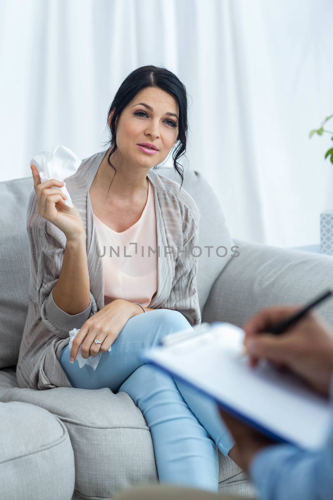 Doctor writing on clipboard while consulting pregnant woman at home