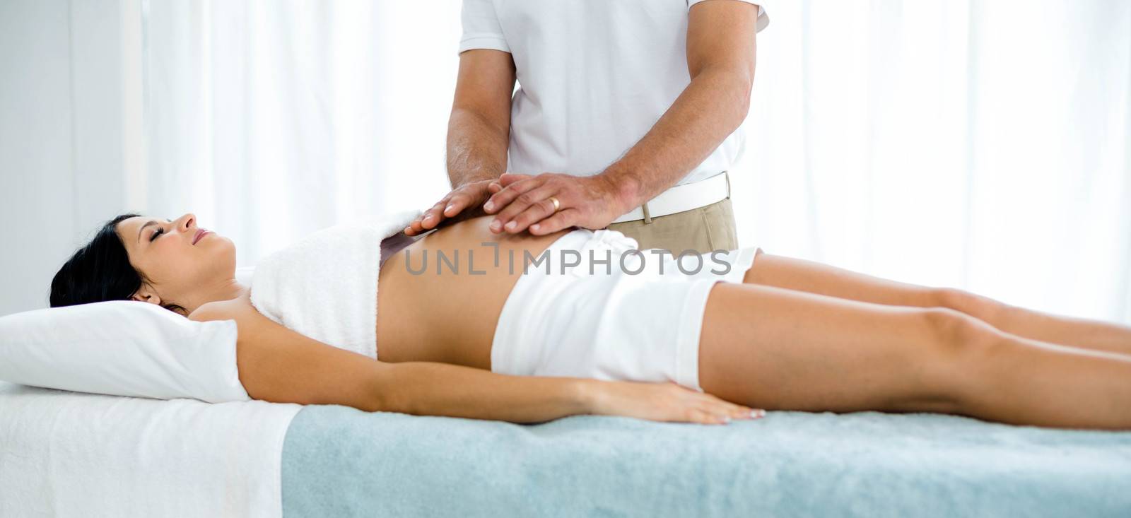 Pregnant woman receiving a stomach massage from masseur at home