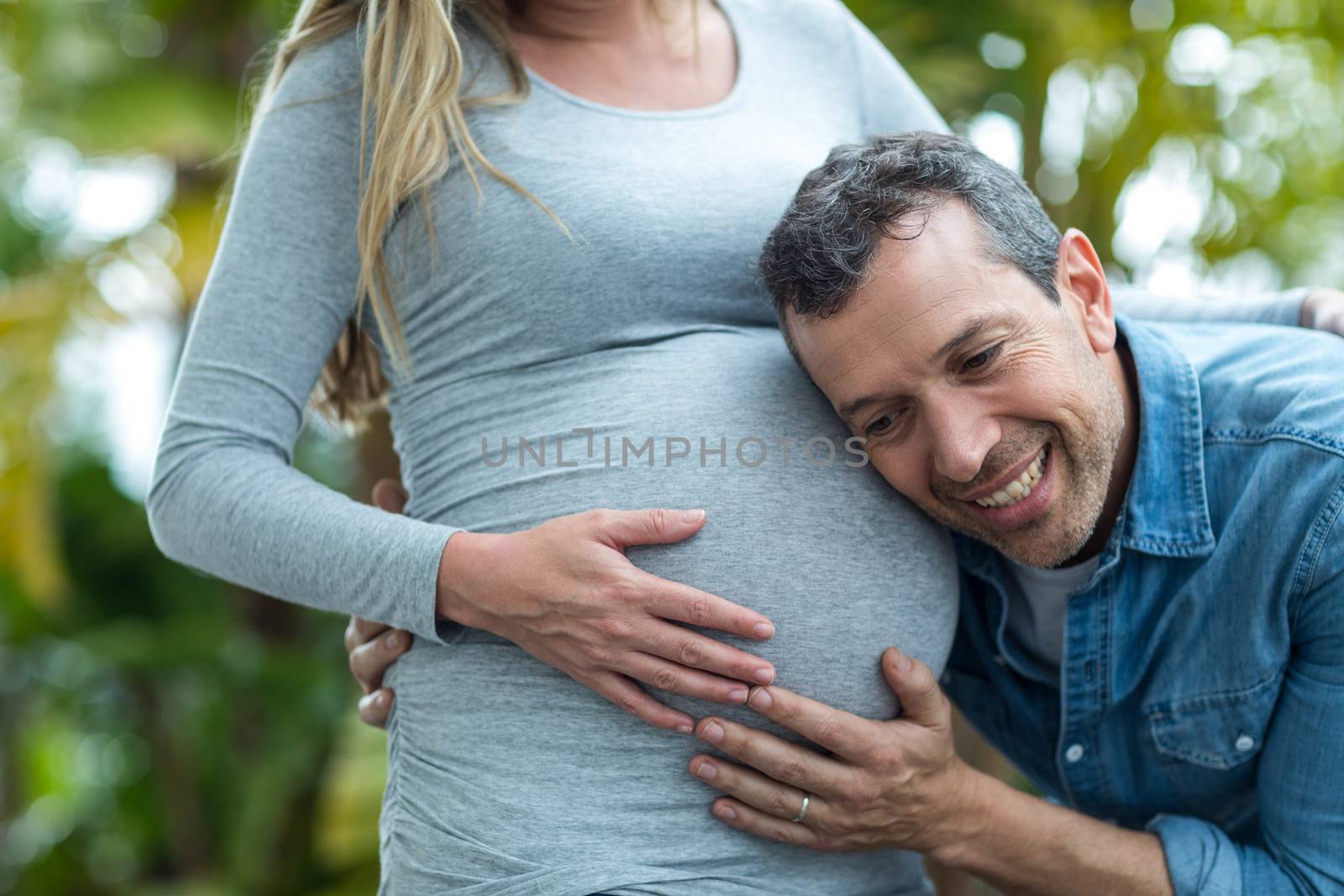 Man listening to pregnant womans stomach by Wavebreakmedia