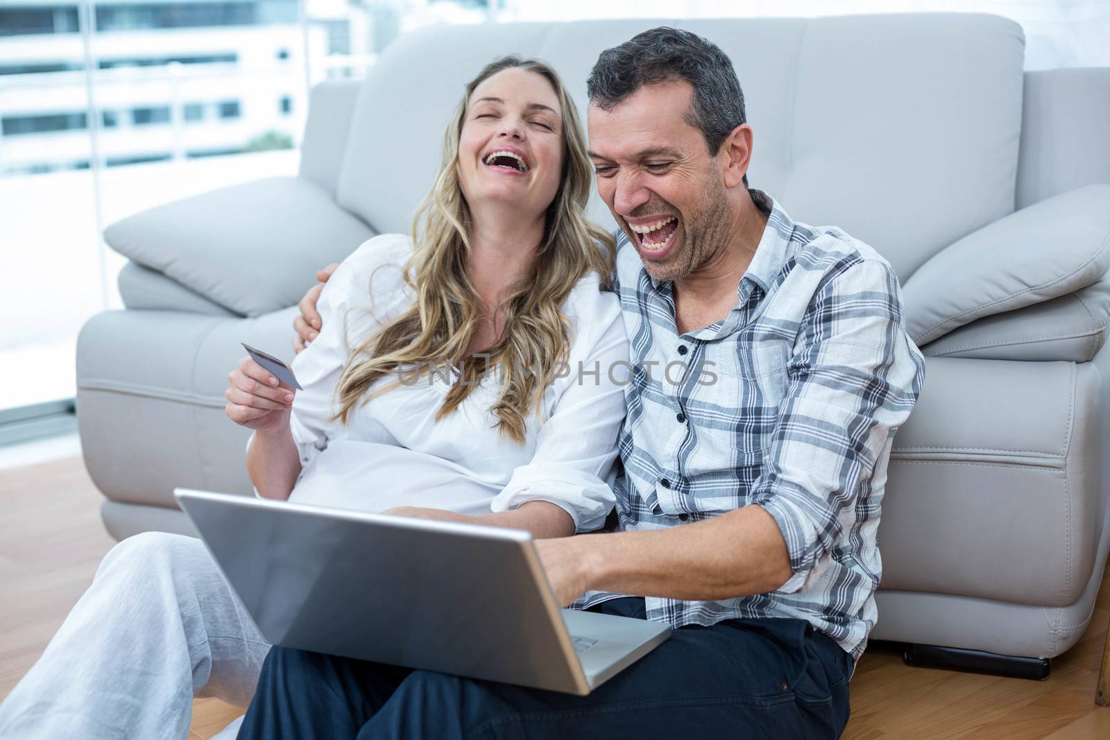 Expecting couple sitting on floor and using laptop