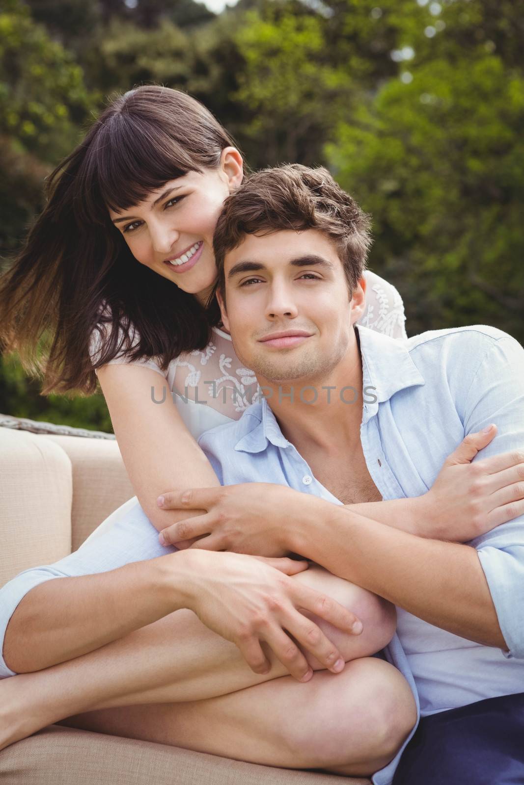 Young couple sitting on sofa and embracing outdoors