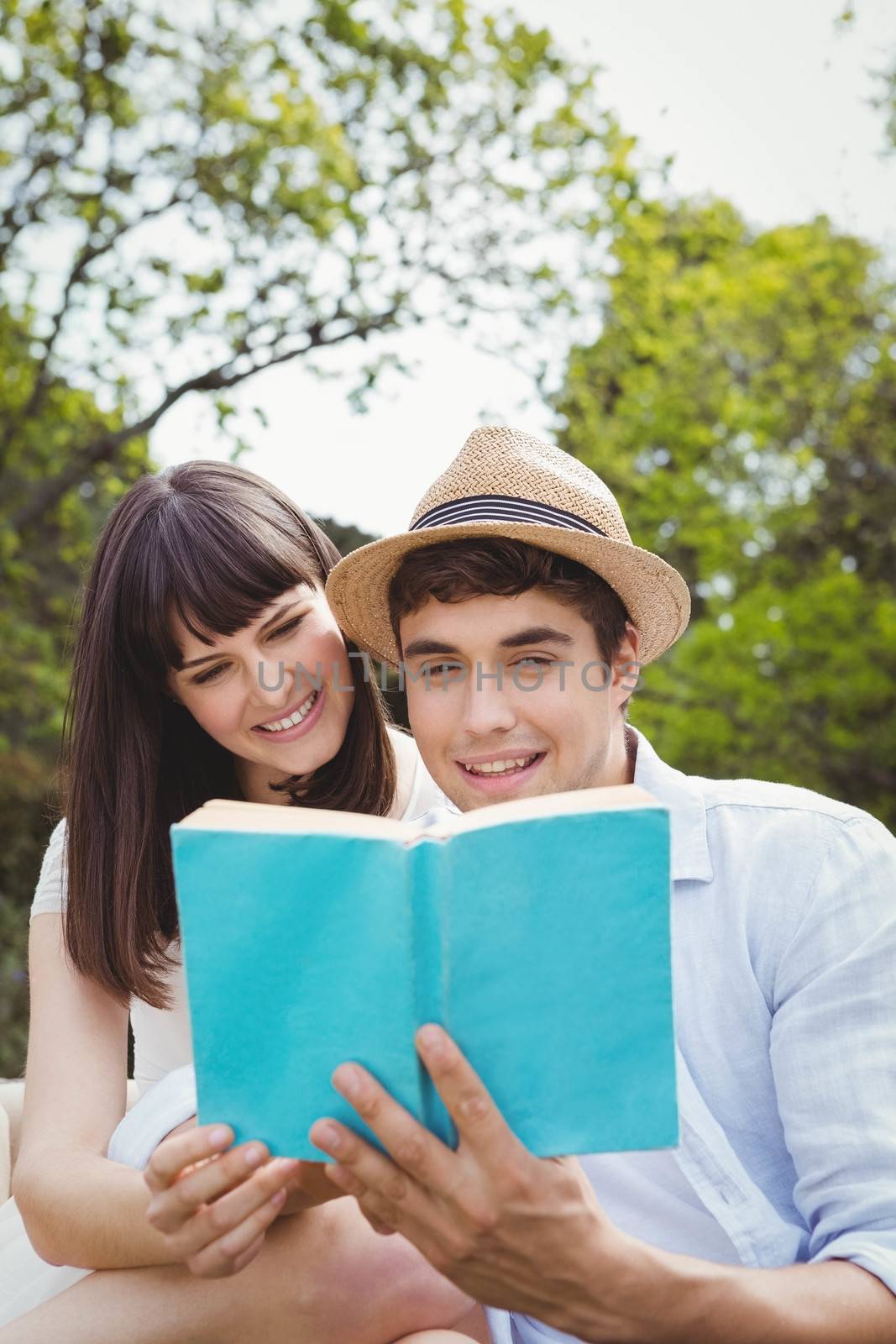 Young couple sitting outdoors and reading a novel