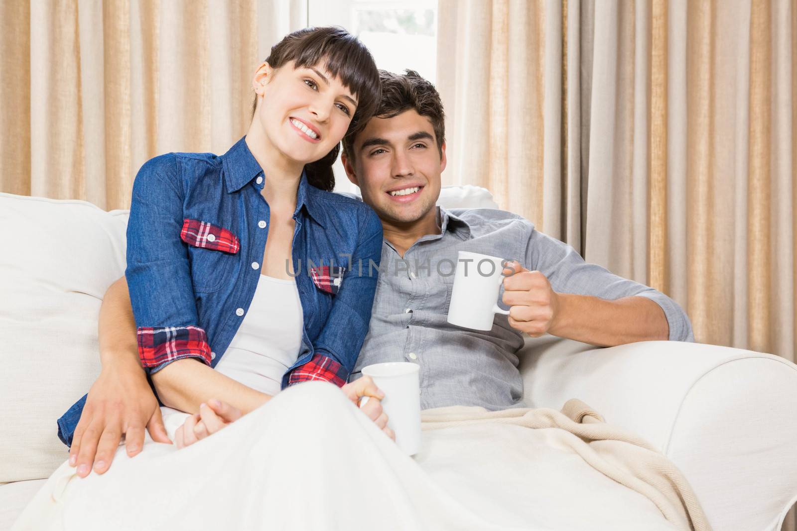 Romantic couple at home relaxing on the sofa having coffee