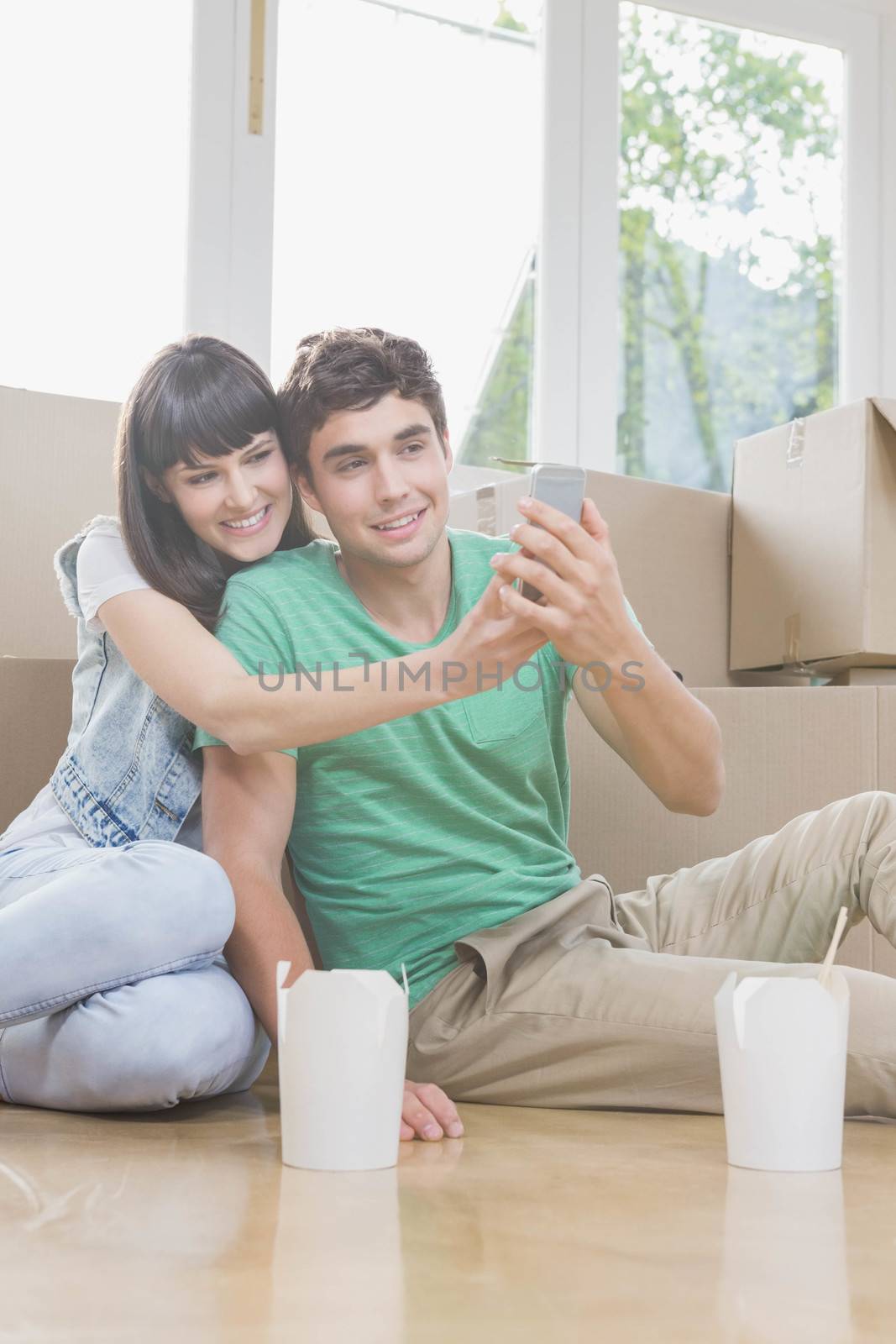 Young couple using mobile phone in their new house