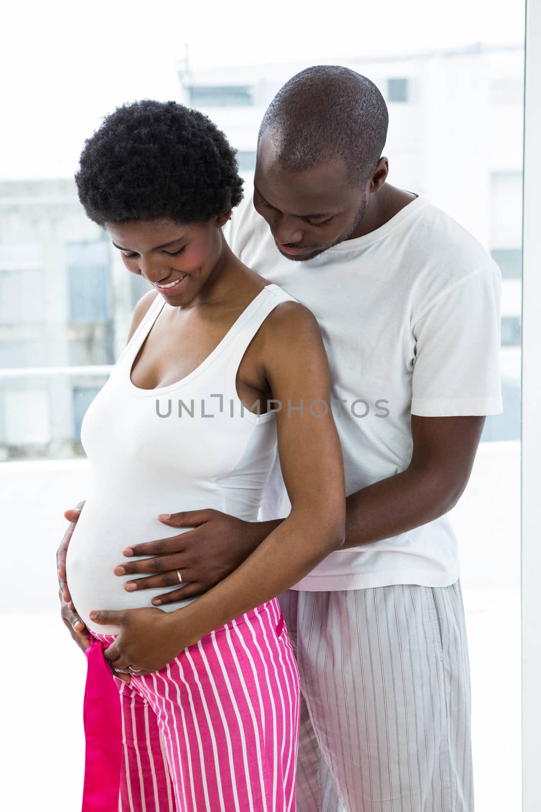 Pregnant couple embracing in bedroom by Wavebreakmedia