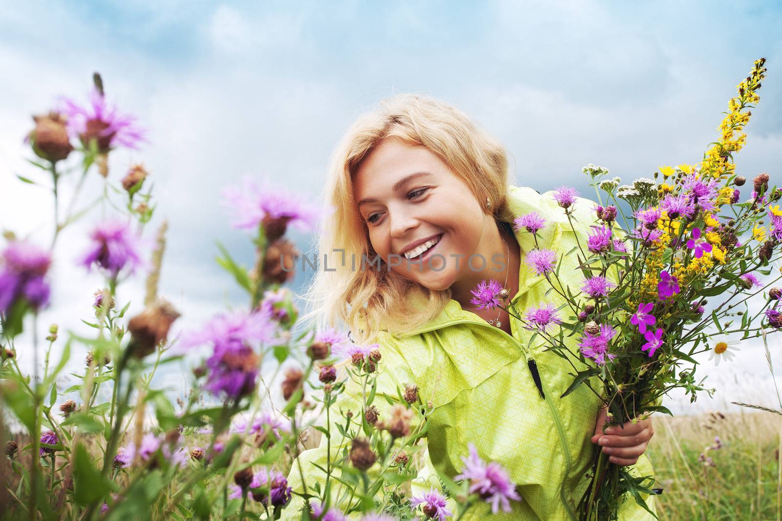 Portrait of young nice woman with flowers in summer environment