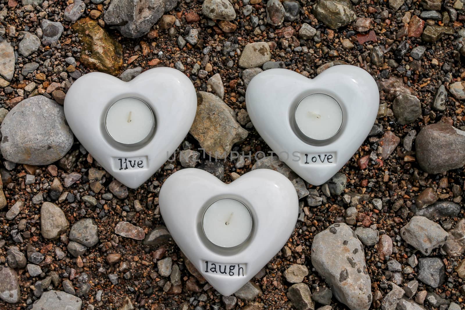 Set of heart shaped candle holders on a pebble river side.