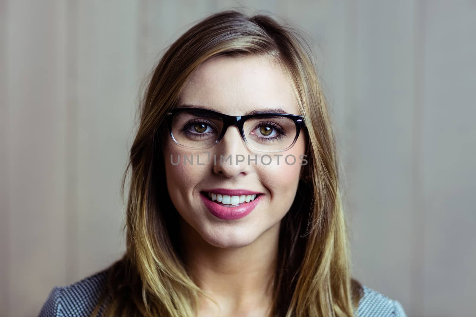 Pretty blonde woman smiling at camera on wooden background