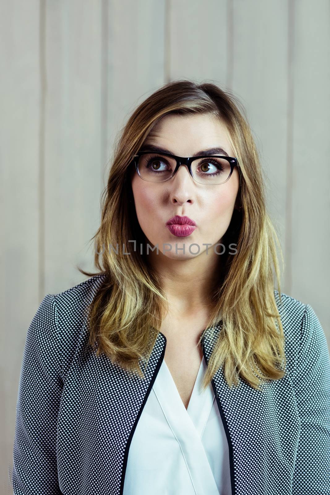 Pretty blonde woman making a funny face on wooden background