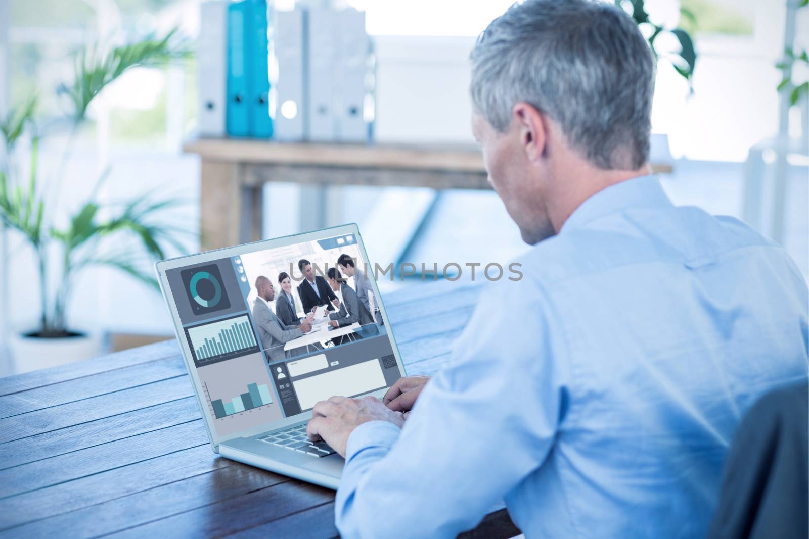 Screen with graphs against businessman working with laptop computer 