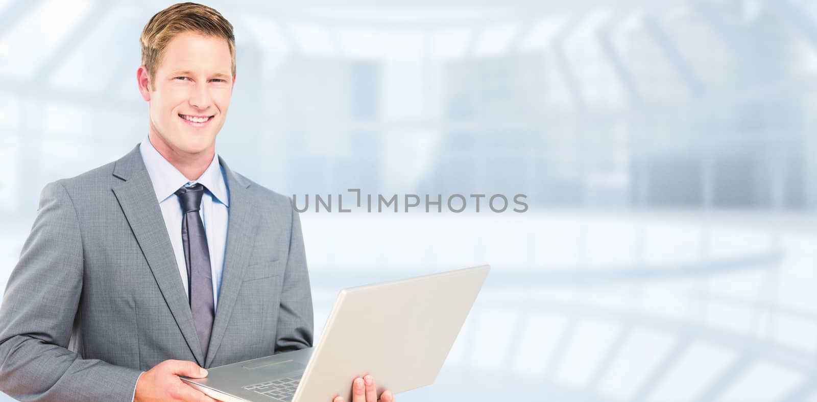 Happy businessman with laptop against modern room overlooking city