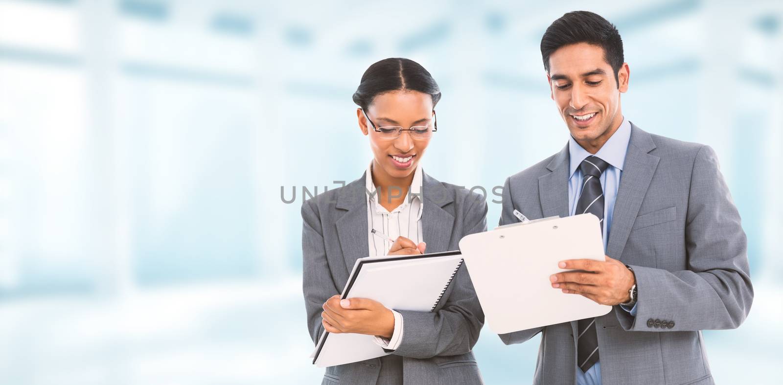 Composite image of smiling business people writing on clipboard and notebook by Wavebreakmedia