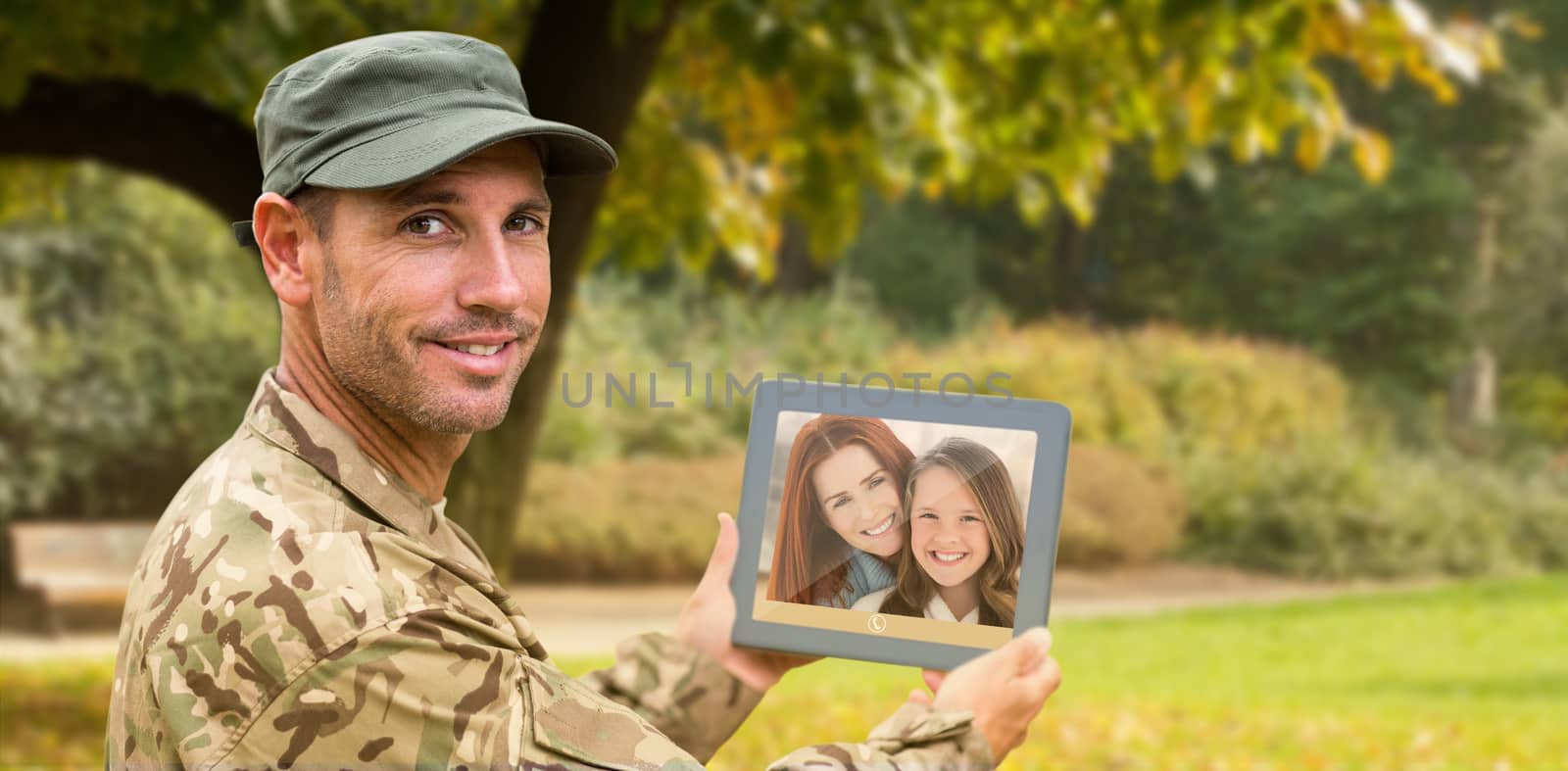 Soldier using tablet pc against trees and meadow in the park