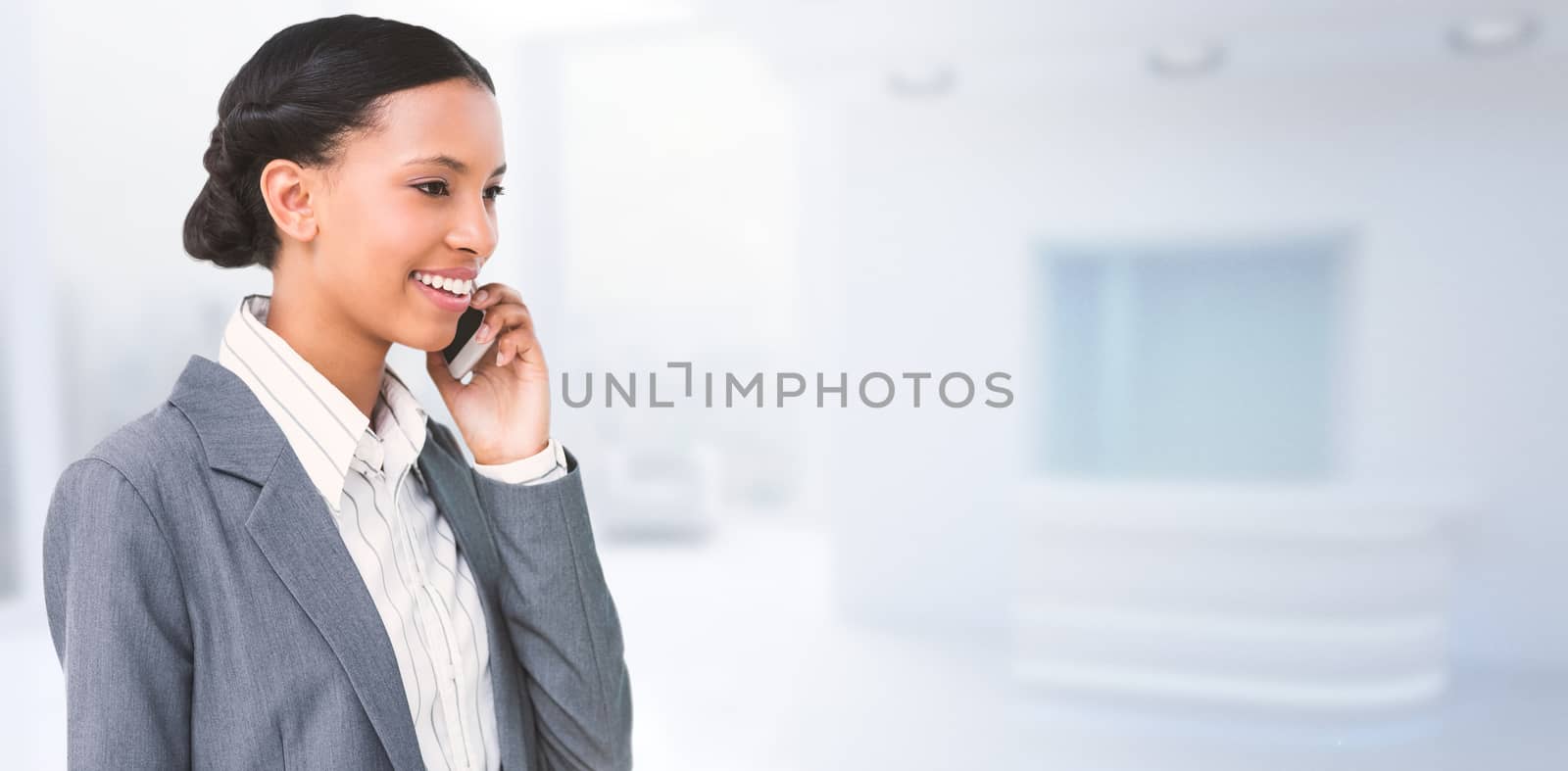 Smiling businesswoman using mobile phone against modern room overlooking city