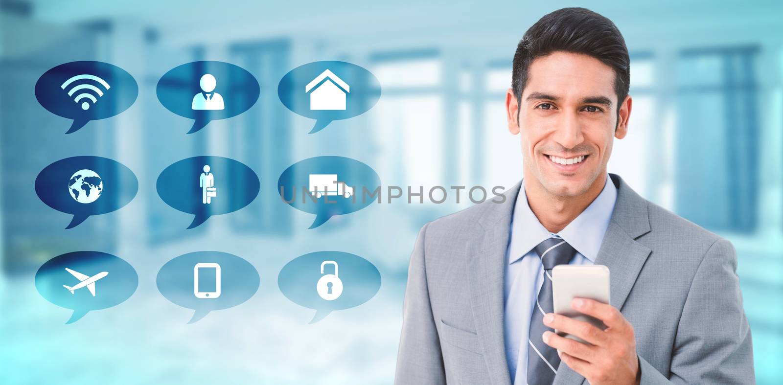 Businessman using mobile phone with colleagues behind against modern room overlooking city