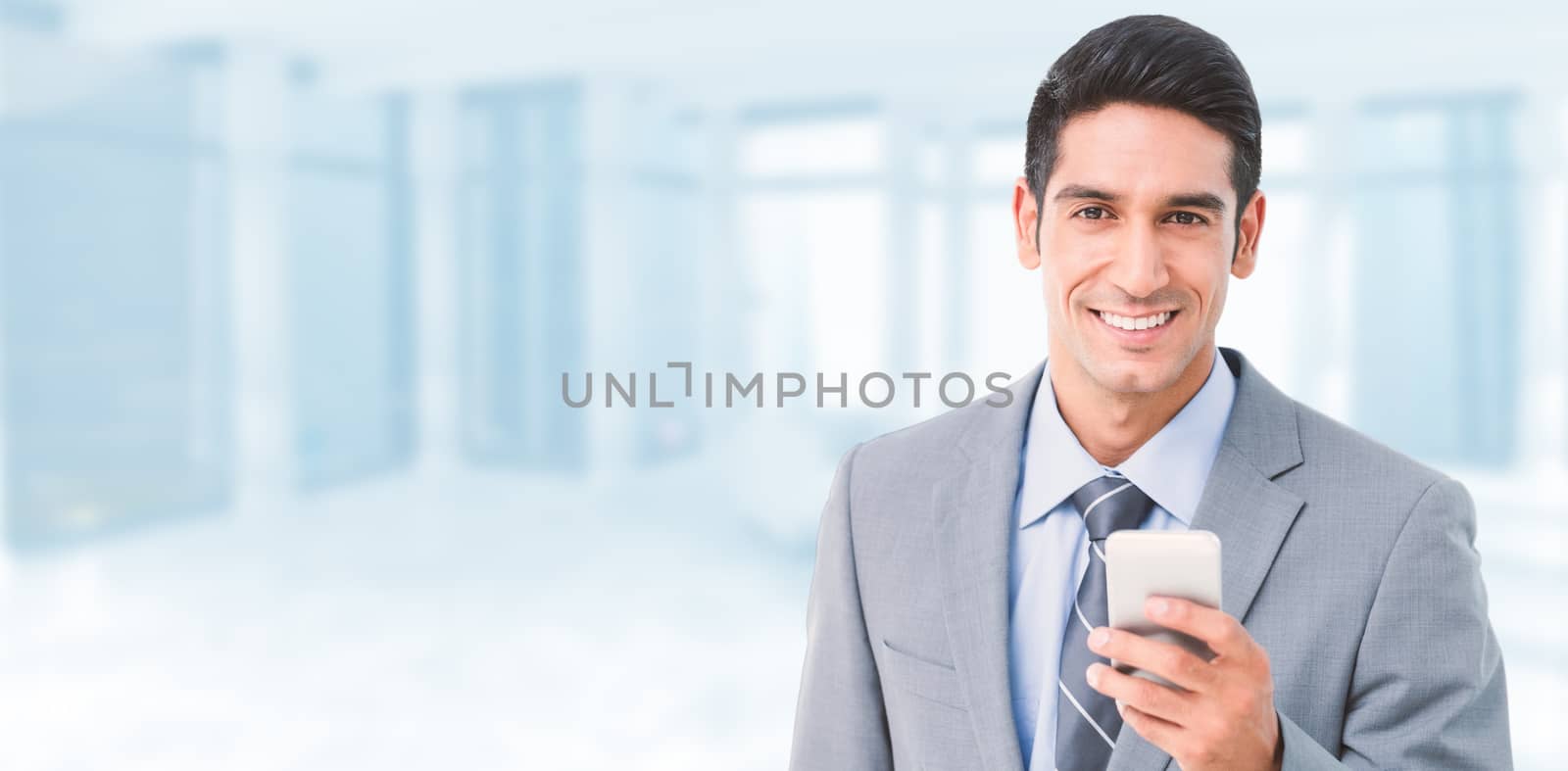 Businessman using mobile phone with colleagues behind against modern room overlooking city