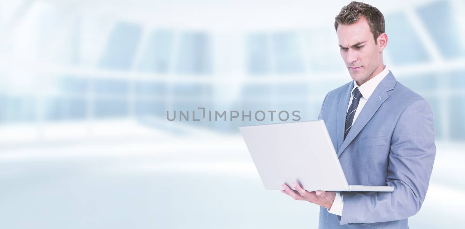 Businessman using laptop against modern room overlooking city