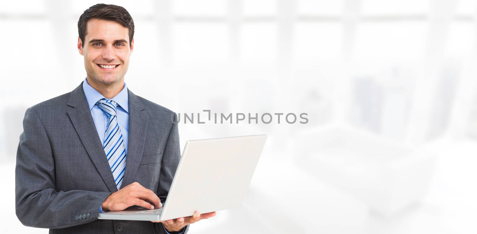 Composite image of portrait of smiling businessman using laptop by Wavebreakmedia