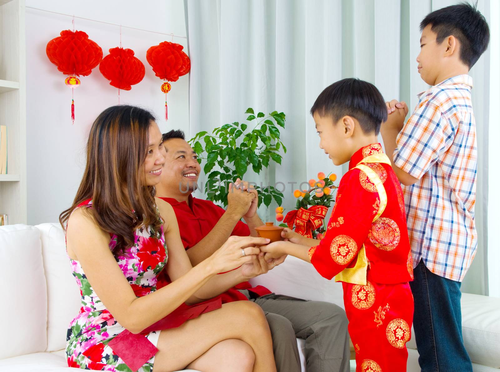 Asian boy presenting tea to his mother during chinese new year