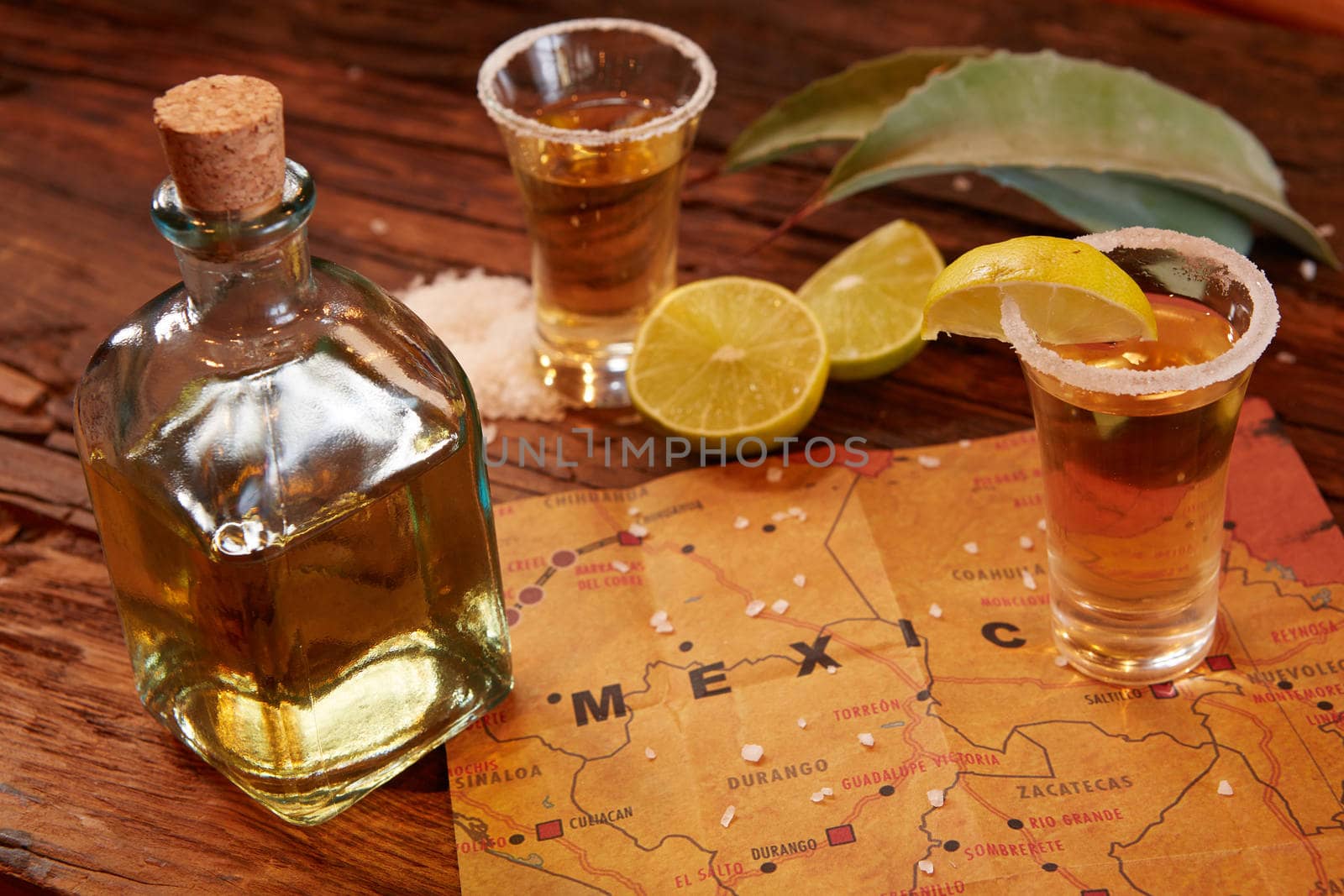 Tequila shot with lime and sea salt on wooden table, selective focus